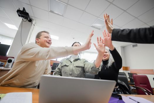 Students and lecturer give a high five in the university classroom