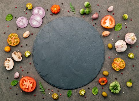 The ingredients for homemade pizza set up on dark stone background.