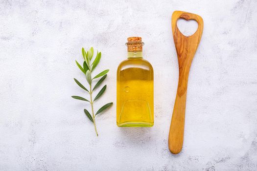 Glass bottle of olive oil and olive branch set up on white concrete background.