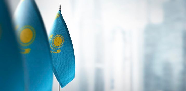 Small flags of Kazakhstan on a blurry background of the city.