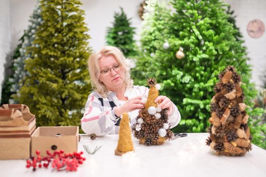 Elderly caucasian woman making cones decoration for christmas