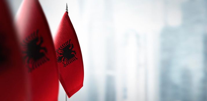 Small flags of Albania on a blurry background of the city.