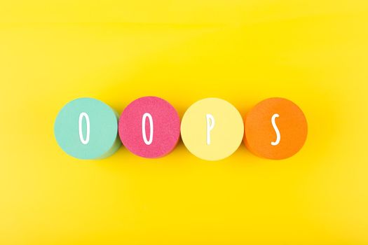 Word oops written on colorful round geometric against yellow background. Trendy minimal concept of emotions expression or excitement