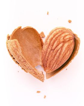 Close up almonds nut shell cracked in heart shape isolated on white background. Love healthy eating concept.