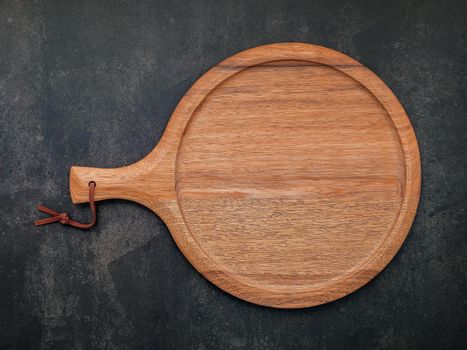 Empty wooden pizza platter set up on dark concrete. Pizza tray on dark concrete background flat lay and copy space.