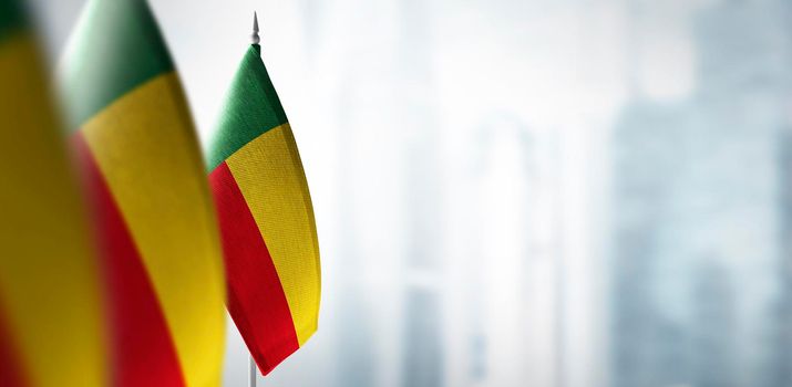 Small flags of Benin on a blurry background of the city.