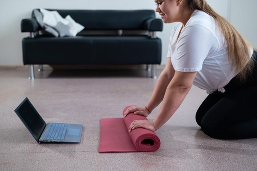 Young chubby woman preparing for an online fitness class. Distance training during the quarantine period.