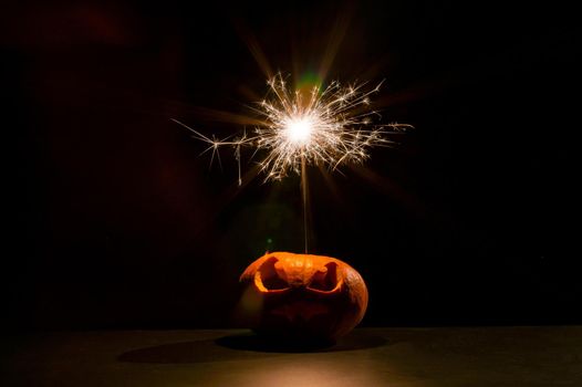 Halloween pumpkin with scary carved grimace and sparklers