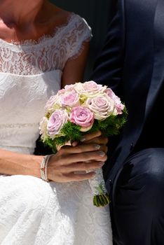 bride wearing a modern wedding bouquet of soft colored roses against a white wedding dress