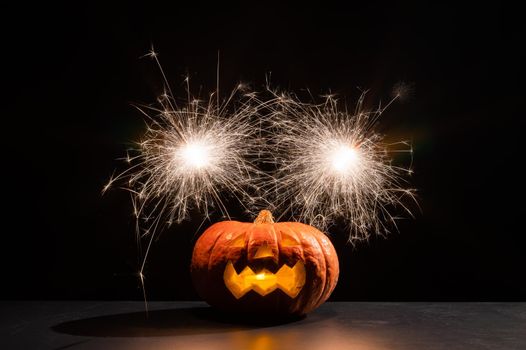 Halloween pumpkin with scary carved grimace and sparklers