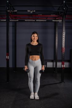 Asian woman doing exercises with dumbbells in the gym