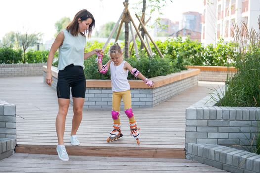 Caucasian woman teaches her daughter to skate on roller skates