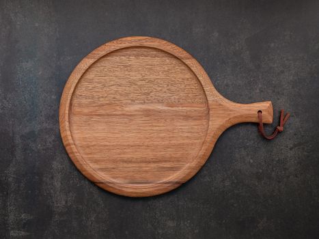 Empty wooden pizza platter set up on dark concrete. Pizza tray on dark concrete background flat lay and copy space.