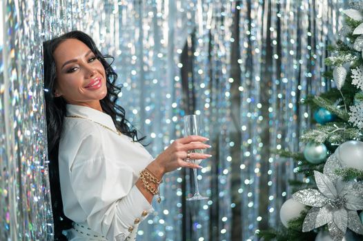 Sexy brunette holding a glass of champagne. Woman wishes a happy christmas.