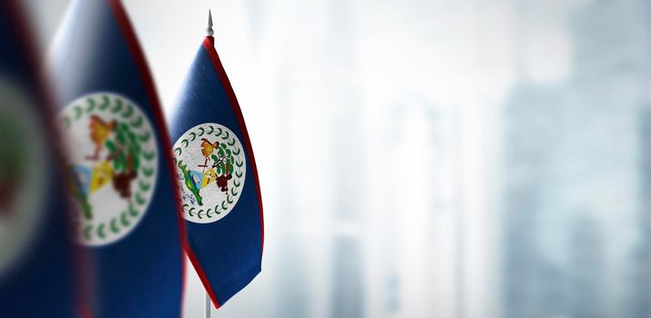 Small flags of Belize on a blurry background of the city.