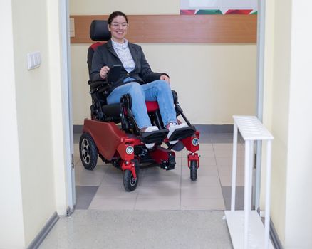 Caucasian woman in electric wheelchair in university corridor