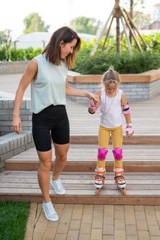 Caucasian woman teaches her daughter to skate on roller skates