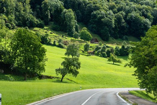 Beautiful green hill landscape in Switzerland Alps. Winding road