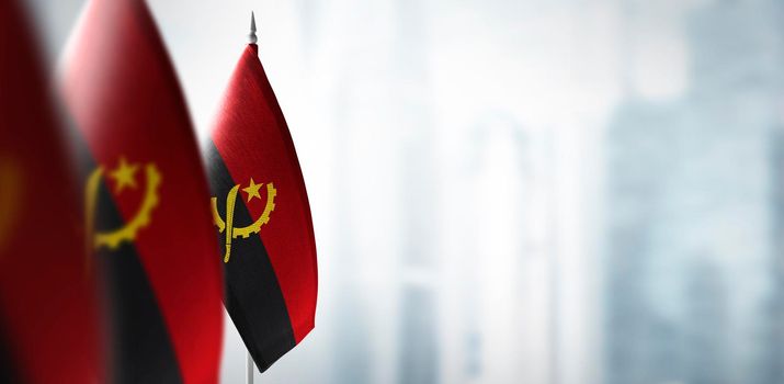 Small flags of Angola on a blurry background of the city.