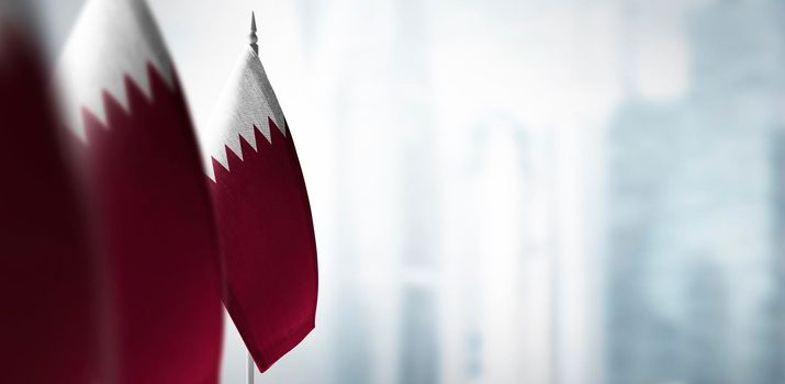 Small flags of Qatar on a blurry background of the city.