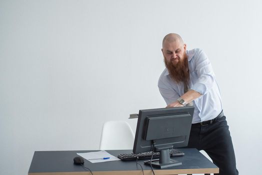 Stressed crazy businessman smashing his computer in office using ax problem concept. The man has problems at work and frustration