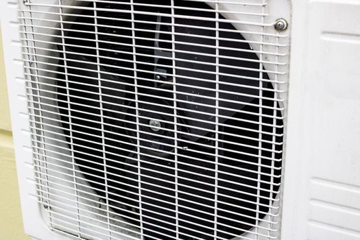 Gray air conditioner fan behind bars close up