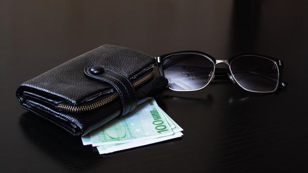 Wallet, sunglasses, euro on a wooden background close up