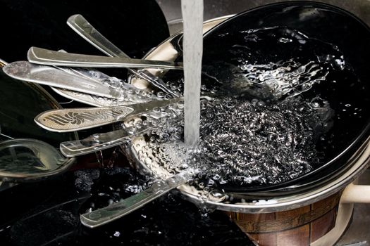 Black dishes and forks in the sink close up