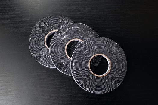 Three reels of double-sided tape on a wooden table