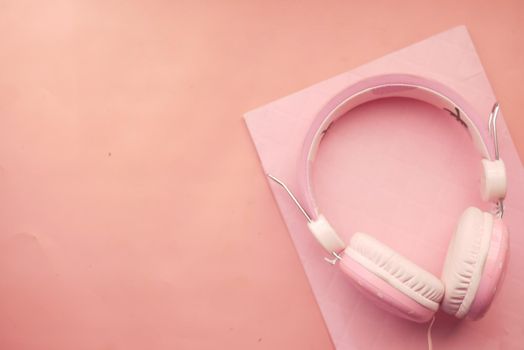 Audio book concept. Headphones and notepad on pink background ,