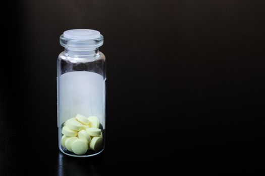 Yellow pills in a glass jar on the table, copy space