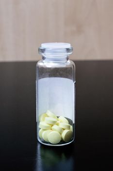 Yellow pills in a glass jar on the table