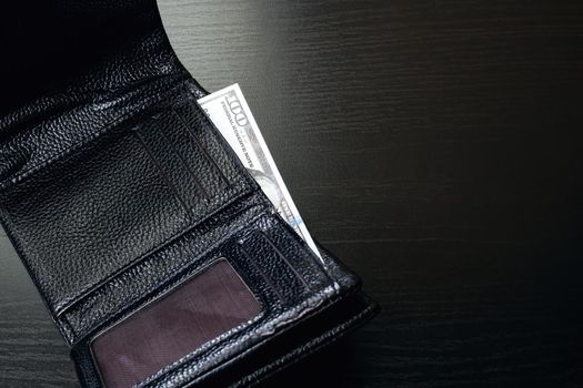 One hundred dollar bill in a black wallet