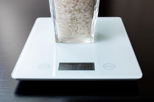 Glass with rice on electronic scales on a wooden table