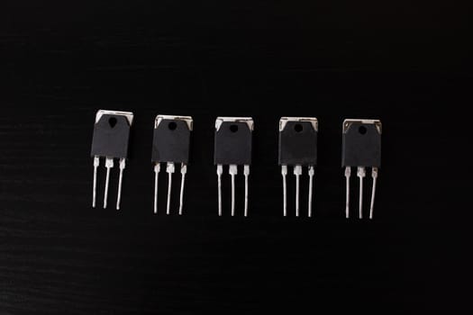 Black transistors on a black wooden table close up