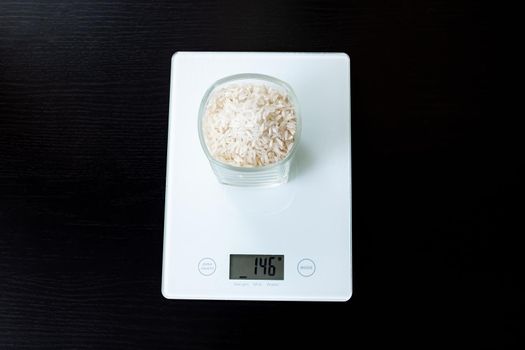 Glass with rice on electronic scales on a wooden table