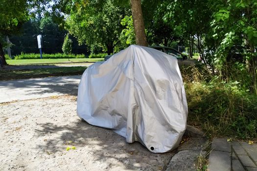 Motorcycle covered with a cover in the yard