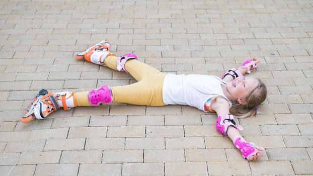 Little girl learns to roller skate and falls. View from above.