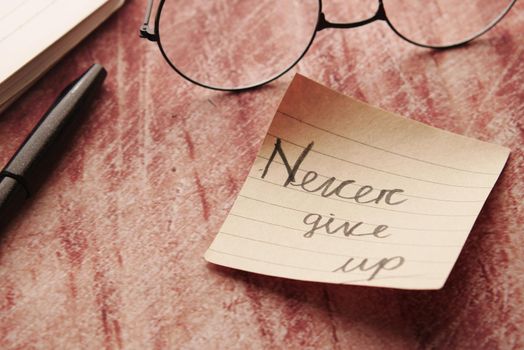 never give up word on stick note on table