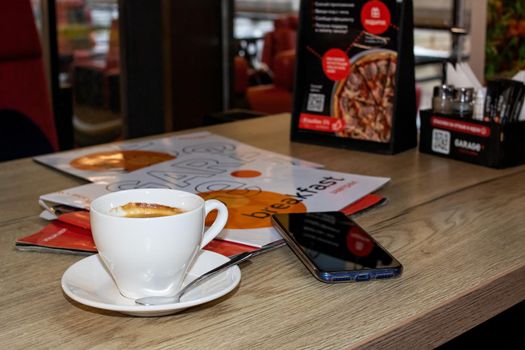 BELARUS, VITEBSK - SEPTEMBER 10, 2020: Cup of coffee and magazines on table