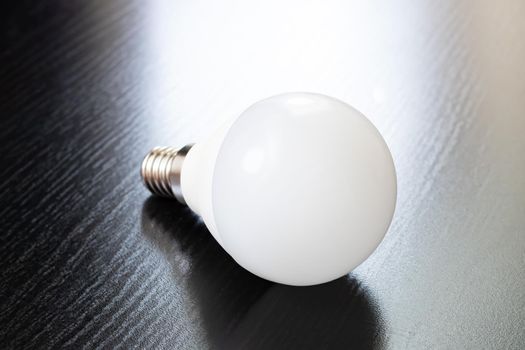 LED light bulb on black wooden table close up