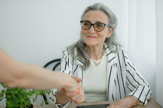 Mature businesswoman is leading an interview with new colleague and shaking their hand at the end. Business people concept.