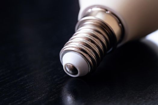 Light bulb base on black wooden table close up