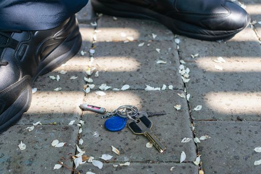 A bunch of keys lying on the sidewalk under the feet of passers-by