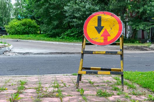 Road sign standing on the side of the road indicating that you must yield to oncoming traffic