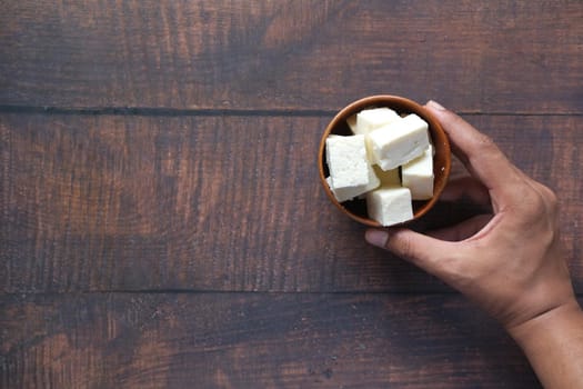 man hand holding a bowl of cheese on table .