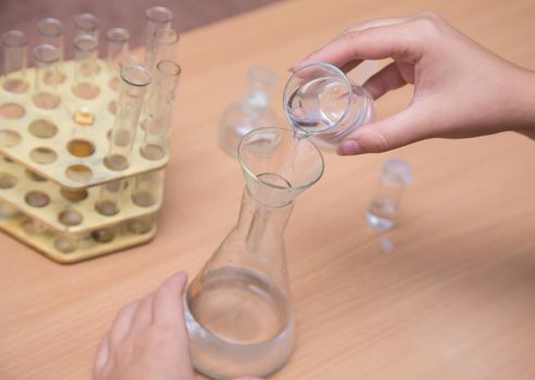 Close-up of a student's hand doing a chemical experiment. A schoolboy performs a task at the workplace. The concept of children's education, teaching knowledge, skills and abilities.