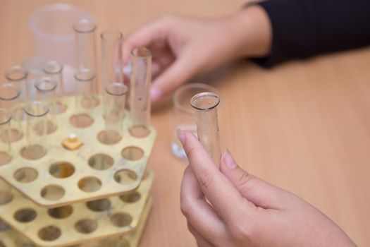 Close-up of a student's hand holding a chemistry test tube. A schoolboy performs a task at the workplace. The concept of children's education, teaching knowledge, skills and abilities.