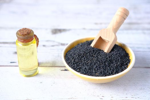 Black Cumin in a bowl with oil in a jar on table..