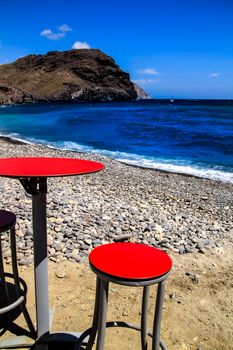 Red table and stool in a bar on Las Negras beach in Cabo de Gata-Nijar natural park